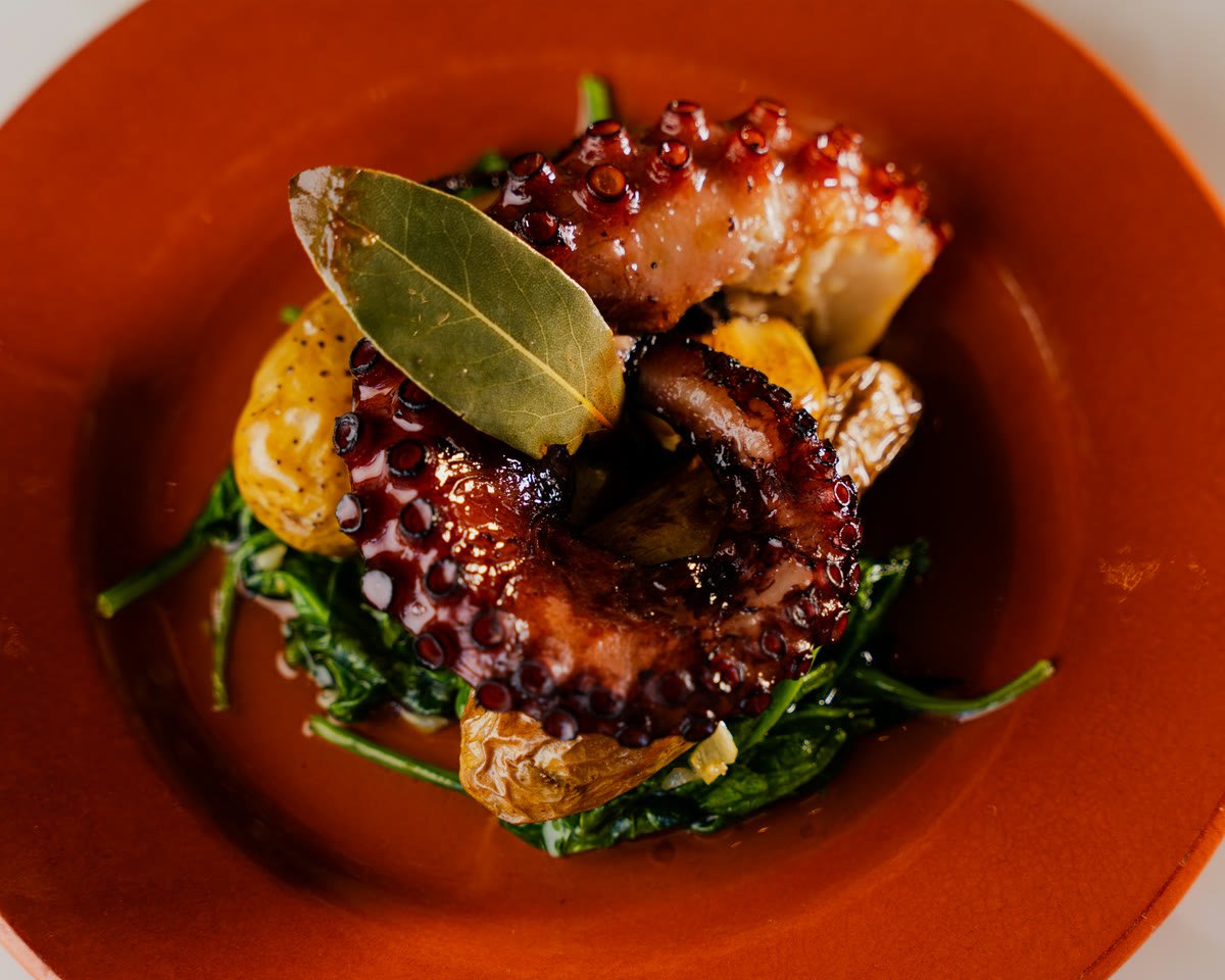 Oven-roasted octopus with crisped edges, fingerling potatoes and spinach